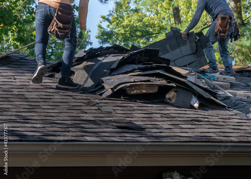 Roofers removing old material from a house in preparation for storm damage repair.	 photo