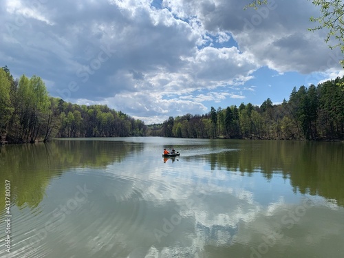 Sunny spring day, rest at the lake. In the distance a boat, a forest. Blue sky, clouds. Serenity, silence, peace, harmony with nature.