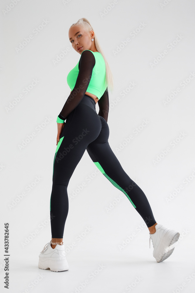 Beautiful fitness woman in leggings. Athletic girl on the gray background Beautiful fitness woman in leggings. Athletic girl on the gray background