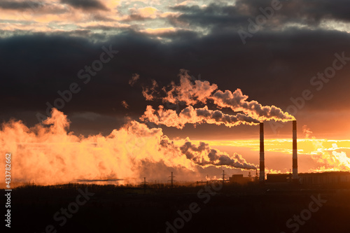 Foto the smoke from the chimneys of the plant during sunset is illuminated by the sun