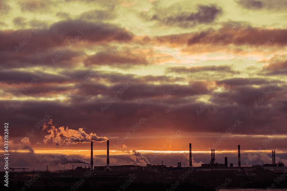 cloudy sky with clouds during sunset and smoking chimneys of an aluminum plant