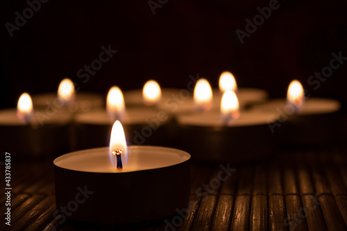 burning candles in the church. tea light closeup with blurred lights in the background on wooden table
