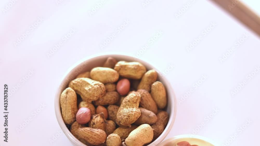 Inside the white bowl are whole peanuts and in a small bowl are groundnuts and the table rotates,Peanut seeds in white bowl rotates, Inside the white bowl are whole peanuts and in a small bowl are groundnuts and the table rotates,Peanut seeds in white bowl rotates,