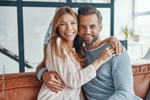 Heterosexual couple smiling and looking at camera while spending time at home