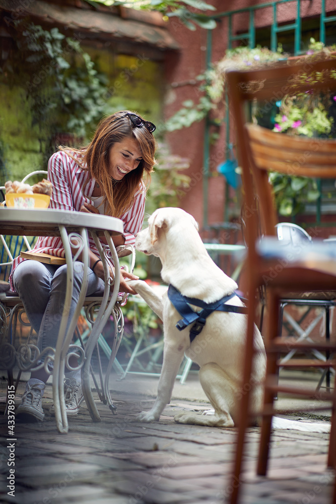 Young girl has a good time with her dog in the bar's garden. Leisure, bar, friendship, outdoor