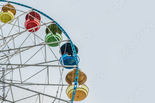 Ferris wheel with multi-colored cabins against a bright blue sky