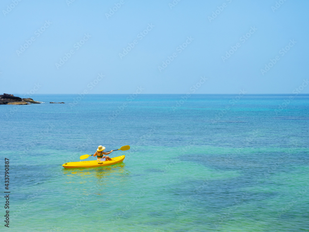 Asian tourist on yellow Kayak boat in tropical island blue sea bright sun in summer. Koh Kood - Thailand