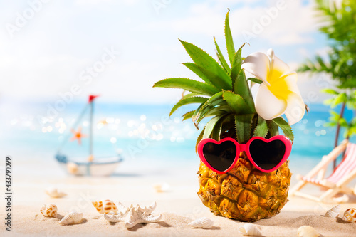 Fototapeta Naklejka Na Ścianę i Meble -  Summer vacation beach concept. Pineapple with sunglasses in heart form. Hipster fruit on the sand against of sea. Summer party idea.
