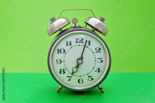 Old vintage alarm clock close up on green background photo