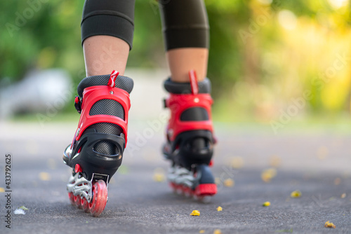 A kid is playing roller skate or roller blade on concrete ground with blurred background of greenery tree in public park. Extreme sport and recreation activity photo. Selective focus at heel's part.