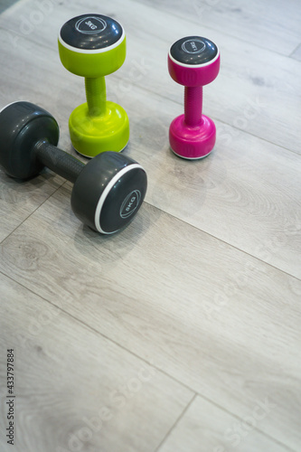 COLOURED DUMBBELLS ON THE WHITE FLOOR OF THE HALL