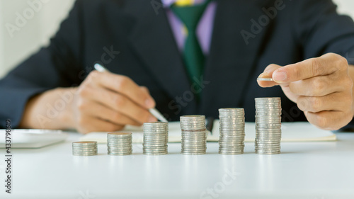 A young businessman puts a pile of coins on his desk, leading the way in calculating and planning finances for savings.