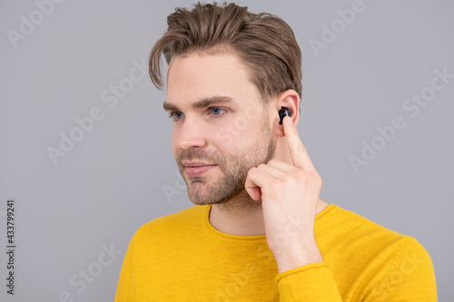 bluetooth headset device accessory. new bluetooth technology. Man point finger at wireless earbud