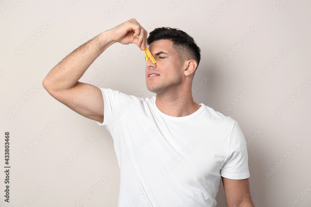 Man with clothespin on beige background. Runny nose concept Man with clothespin on beige background. Runny nose concept