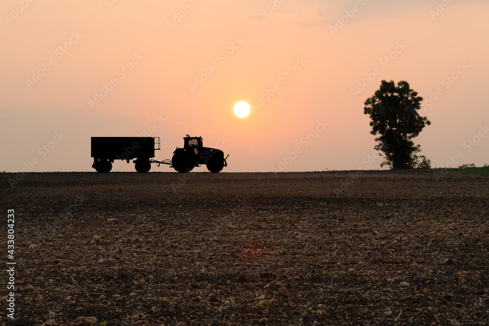 Fototapeta premium Silhouette tractor at hill farm