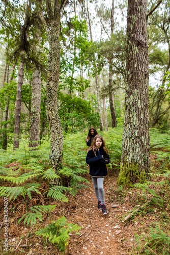 cute young girl and her mom walking in a beautiful forest