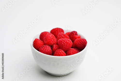 Bowl of fresh raspberries on white background. Flat lay, top view, copy space. Raspberries isolated on white background. Raspberries Clipping Path. Mint Raspberries macro studio photo. 