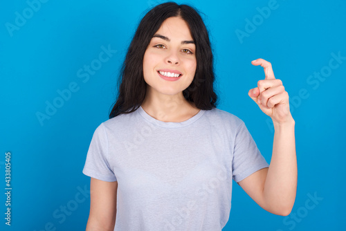 young beautiful tattooed girl wearing blue t-shirt standing against blue background pointing up with fingers number nine in Chinese sign language Jiu