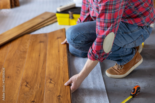 Wallpaper Mural Man worker installing laminate flooring. Wooden laminate floor plank and tools Torontodigital.ca