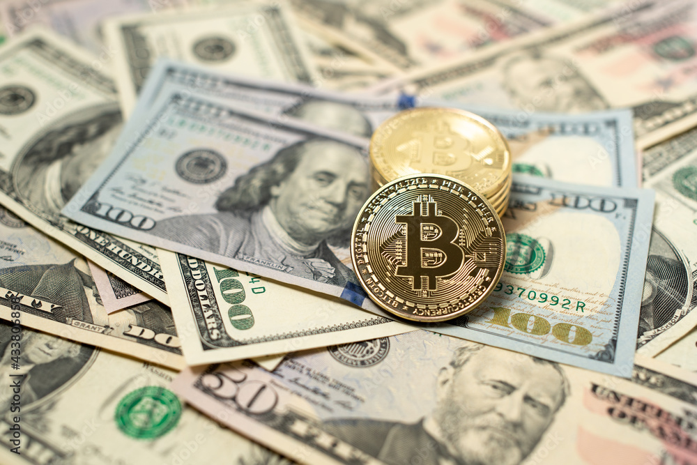 Bitcoin coin on one hundred dollar banknotes from united states of america. Digital crypto currency and US dollar currency. Gold shining coins on piled up cash Bitcoin coin on one hundred dollar banknotes from united states of america. Digital crypto currency and US dollar currency. Gold shining coins on piled up cash