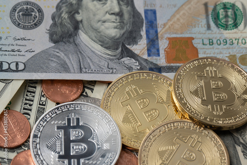 Gold and silver Bitcoin next to 100 dollar banknote. Trading crypto and fiat money.
