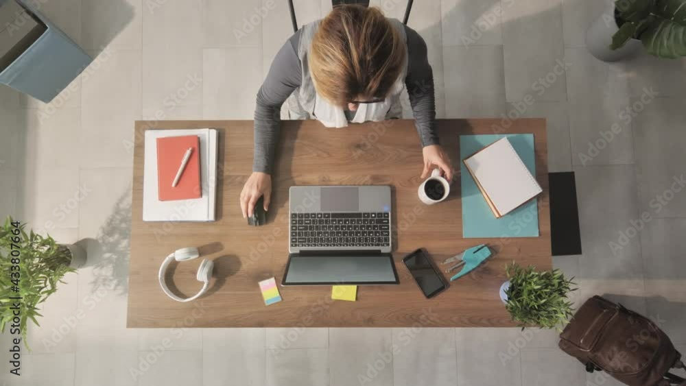 overhead top down view of woman using laptop computer at her desk,caucasian female businesswoman typing at the notebook drinks coffee shot from above