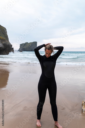 Mid adult female surfer in wetsuit at beach on cloudy day