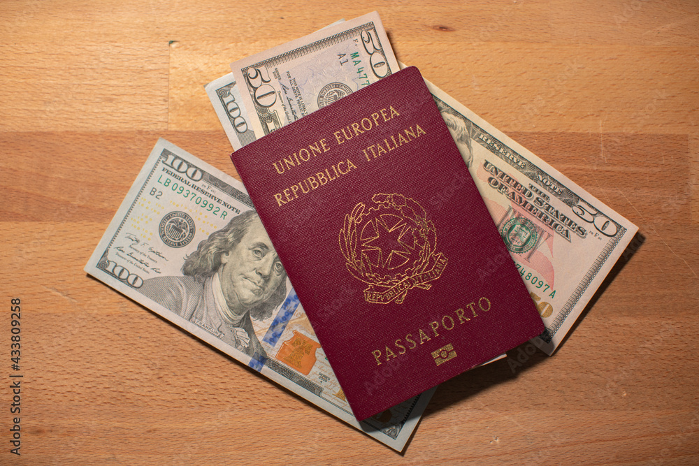 Dollar bills inside and next to italian passport. One hundred dollar banknotes. Concept of travel from italy to USA Dollar bills inside and next to italian passport. One hundred dollar banknotes. Concept of travel from italy to USA