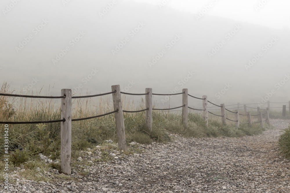 Foggy rocky road with wooden fences