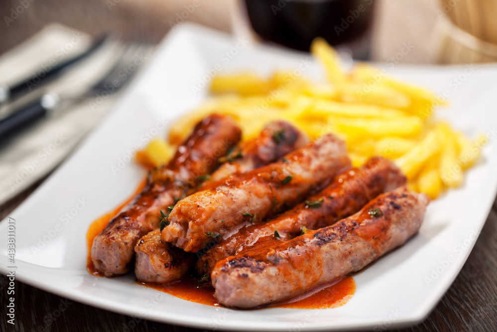 Sausages and roasted potatoes on a plate. High quality photo.