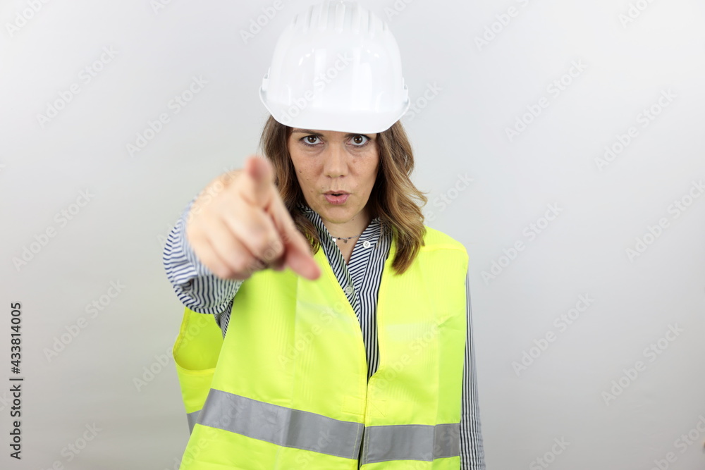 Woman engineer with hardhat pointing displeased and frustrated to the camera, angry and furious at you.