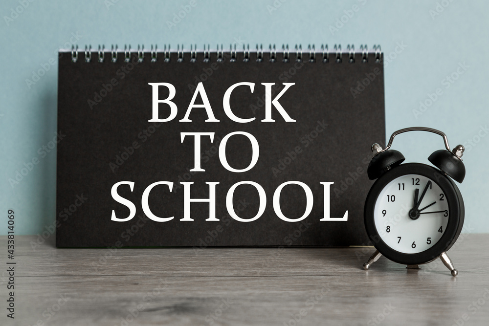 A word BACK TO SCHOOLon black notebook with clock. Concept for time management and business. A word BACK TO SCHOOLon black notebook with clock. Concept for time management and business.