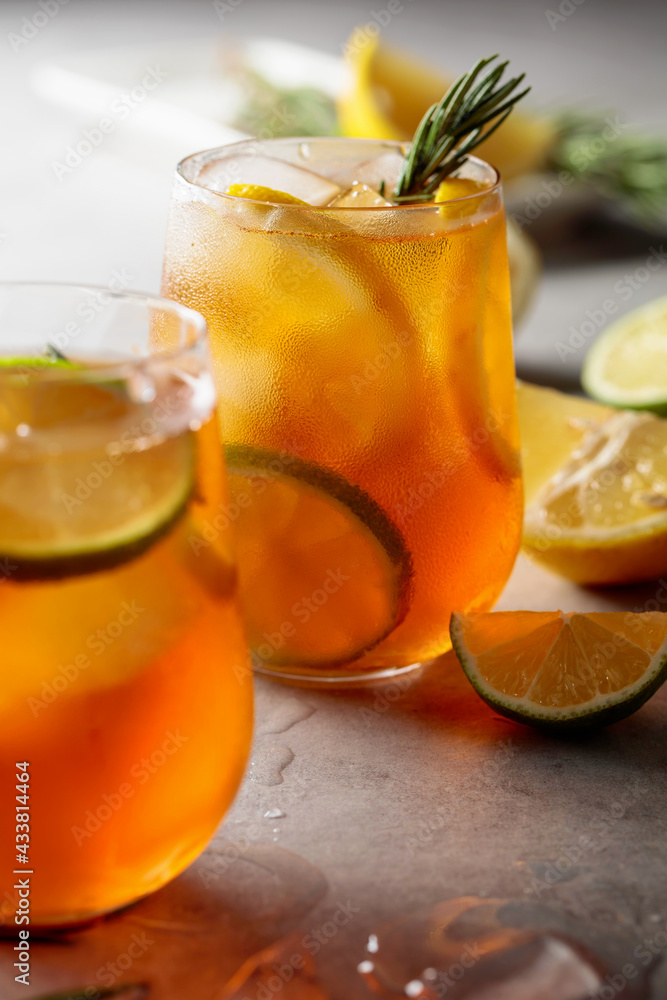 Fototapeta premium Iced tea with lemon, lime and ice garnished with rosemary twigs.