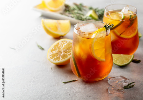 Iced tea with lemon, lime and ice garnished with rosemary twigs.
