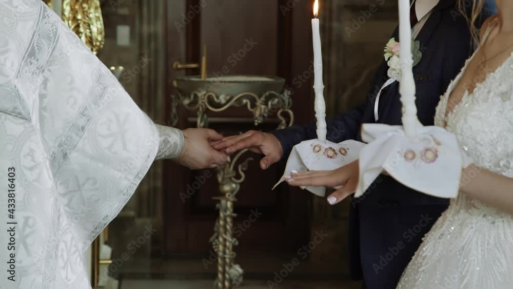Priest Rings Orthodox priest in white robe with gold cross exchanges wedding rings ...