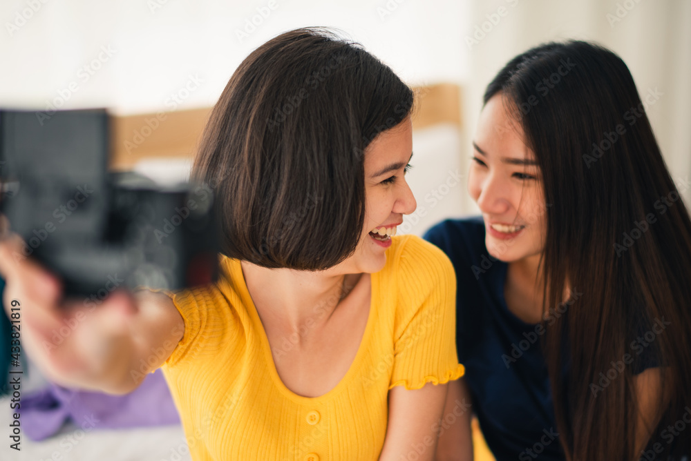 Young beautiful Asian couple love friend woman take picture selfie by digital camera on bed when summer trip which smiling and felling happy, LGBT woman love Travelling vacation trip concept Young beautiful Asian couple love friend woman take picture selfie by digital camera on bed when summer trip which smiling and felling happy, LGBT woman love Travelling vacation trip concept