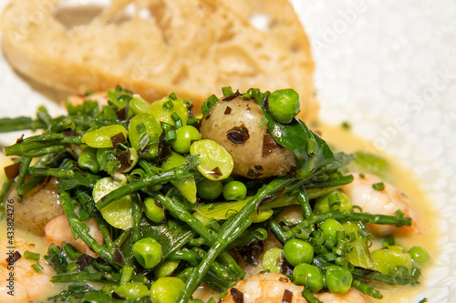 A delicious plate of potatoes fricassee with tiger prawns and green peas photo