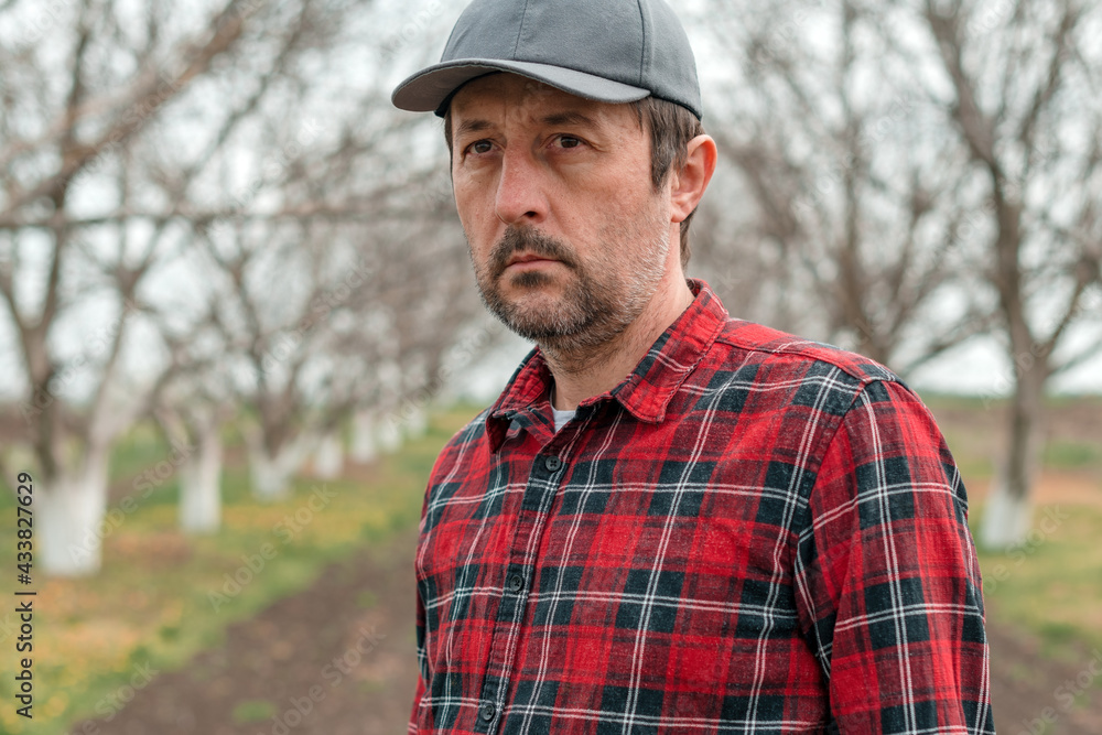 Portrait of handsome confident farmer with baseball cap and flannel shirt in walnut fruit orchard Portrait of handsome confident farmer with baseball cap and flannel shirt in walnut fruit orchard