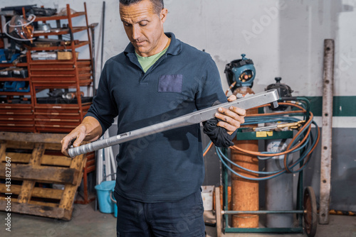 Caucasian mechanic standing with torque wrench in hands in workshop. Repair shop concept.