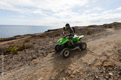 A man riding ATV in sand in protective helmet