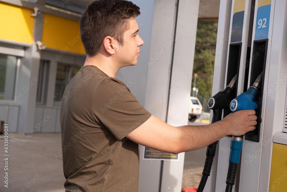 A man takes a pistol at a gas station. Refueling a car with fuel at a gas station. Automotive industry or transportation concept. A man takes a pistol at a gas station. Refueling a car with fuel at a gas station. Automotive industry or transportation concept.