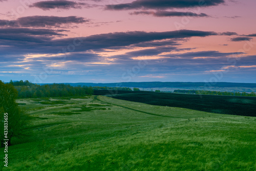 Green hills and pink sky at sunset.