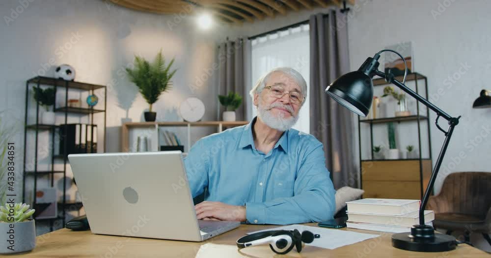 Smiling aged man spending leisure time at home with laptop Smiling aged man spending leisure time at home with laptop
