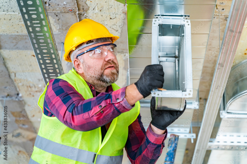 Adult man standing in the ladder and repairing the ventilation system Adult man standing in the ladder and repairing the ventilation system