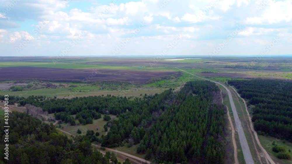 A bird's-eye view of the road between the forest and green fields. Beautiful highway landscape, green fields, green trees. video from a quadrocopter A bird's-eye view of the road between the forest and green fields. Beautiful highway landscape, green fields, green trees. video from a quadrocopter