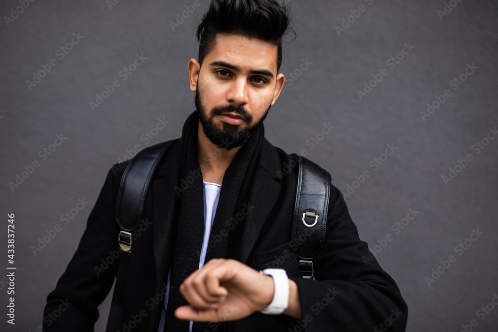 Handsome young man looking at his watch while standing at the street Handsome young man looking at his watch while standing at the street
