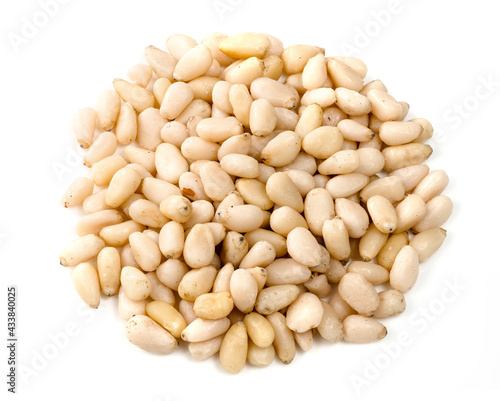 handful of unpeeled pine nuts closeup on white