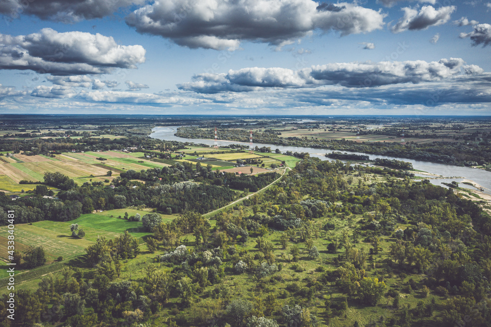 Fields and river under moody cloudy sky aerial view