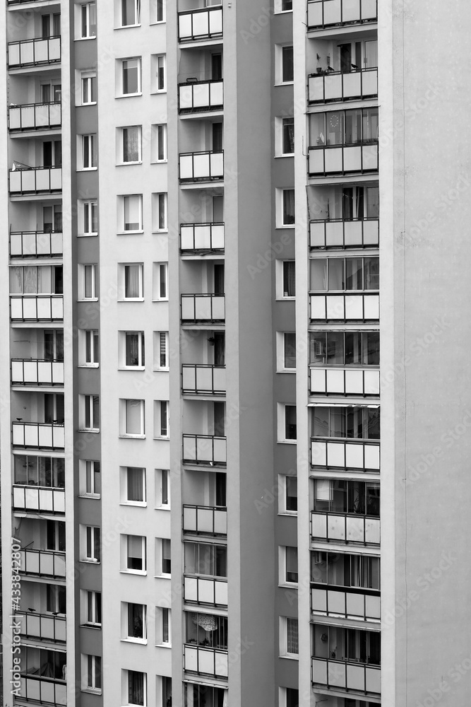 Urban stone jungle. Multiple windows on a large building in the city. Fragment of the facade of high-rise residential buildings. Black and white view
