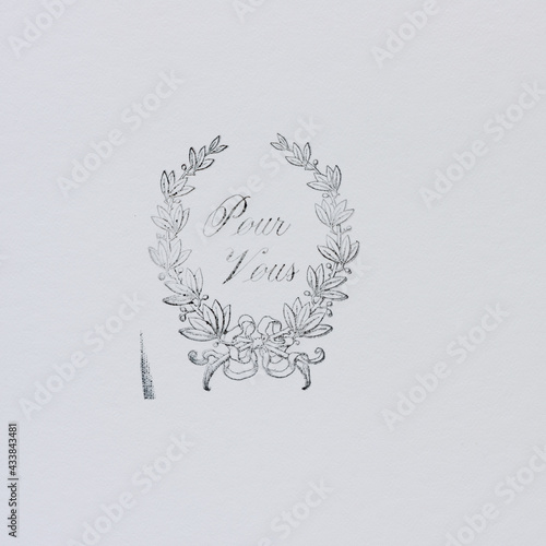 rubber stamp impression of a decorative floral motif with the message in french of pour vous (for you) on white paper photo